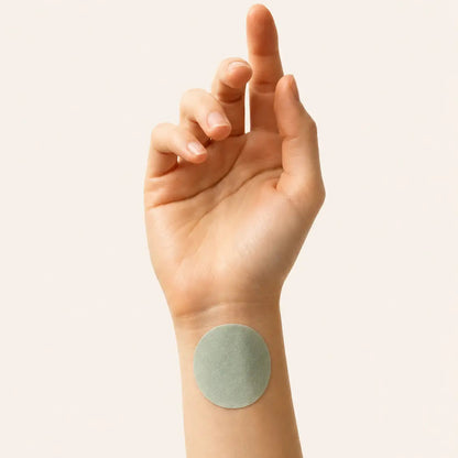 Hand with a green adhesive patch on a plain background
